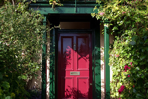 Red door with green frame creating charming house entrance, surr, a Photo by Studio ANNA