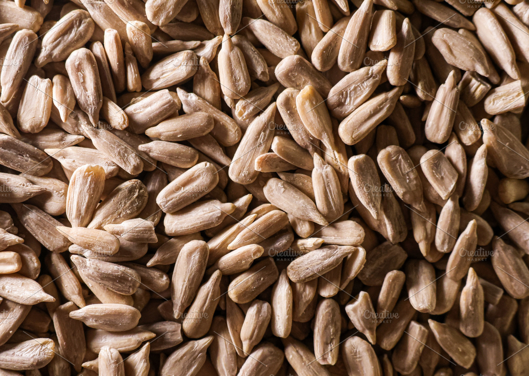 Dried edible shelled sunflower seeds creating a rustic natural f, a Photo by Studio ANNA