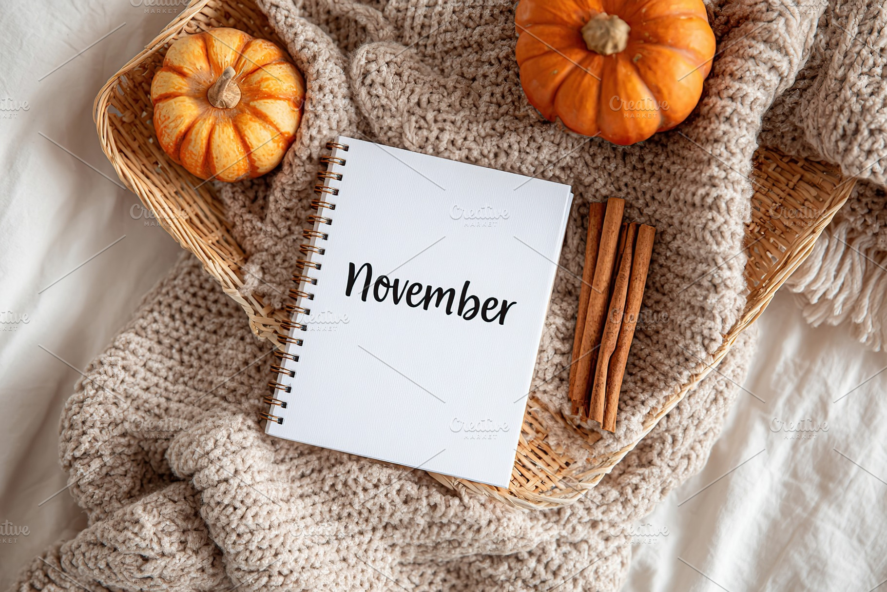 Cozy November setting with pumpkins, cinnamon sticks, and a knitted blanket, a Background Photo by AlyaAnd