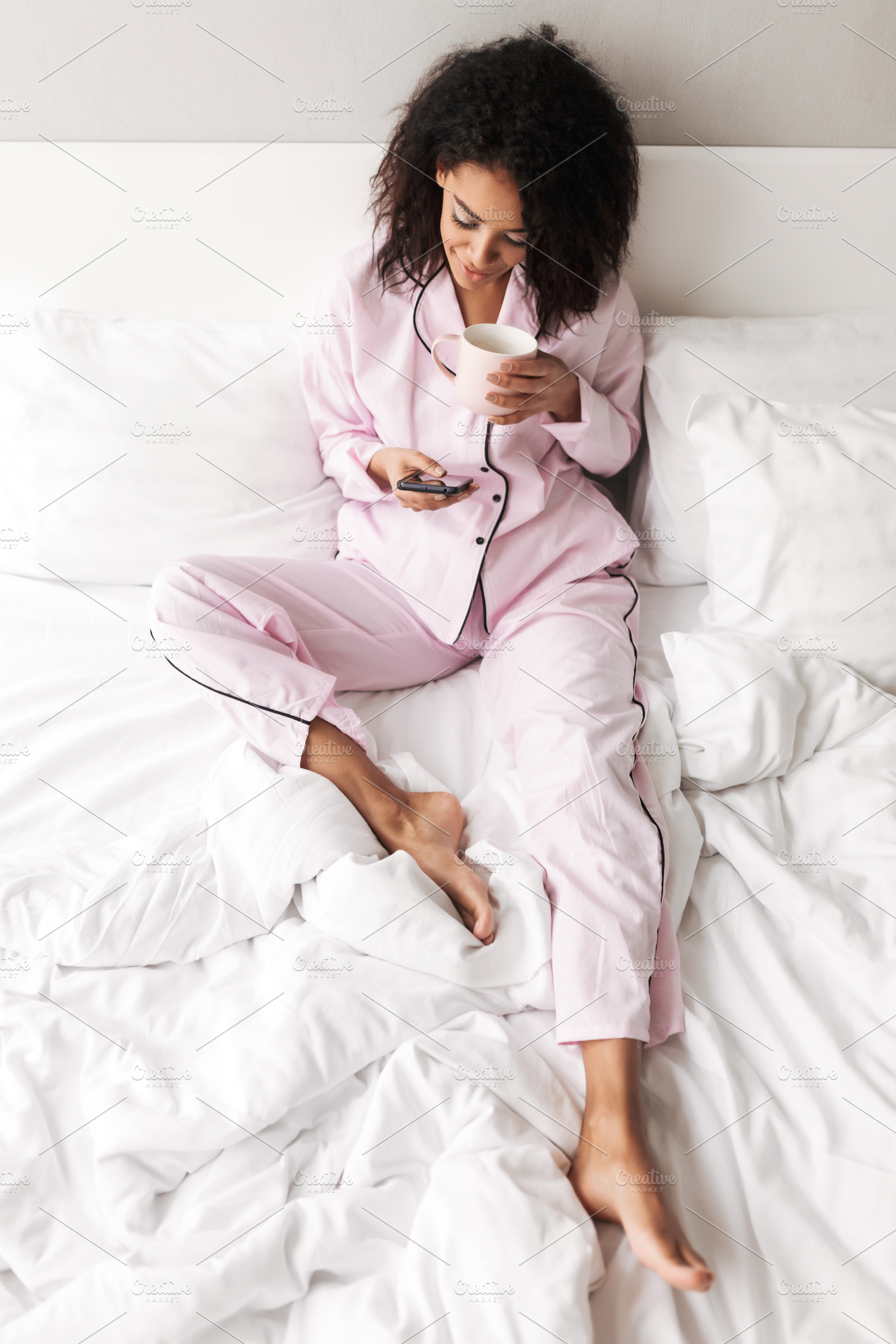 Lady with dark curly hair in stock photo containing blanket and pillows, a Person Photo by Garetsworkshop