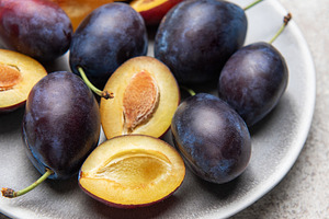 Fresh plums on plate showing halved fruit composition, a Food & Drink Photo by Olena Rudo