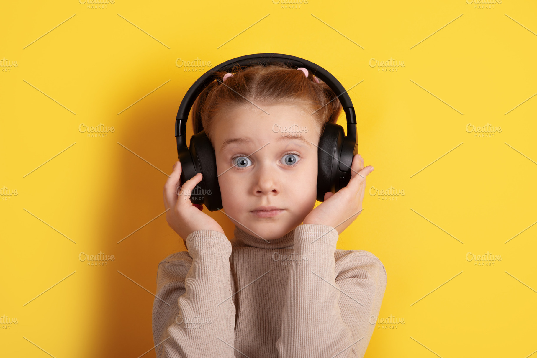 Young girl with headphones on yellow background, expressing surp, a Person Photo by Ales Munt