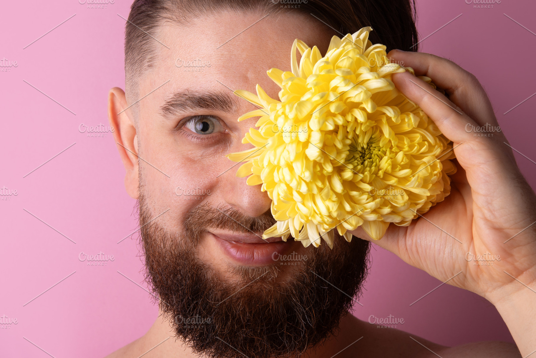 Smiling bearded man covering one eye with a bright yellow chrysa, a Person Photo by Ales Munt