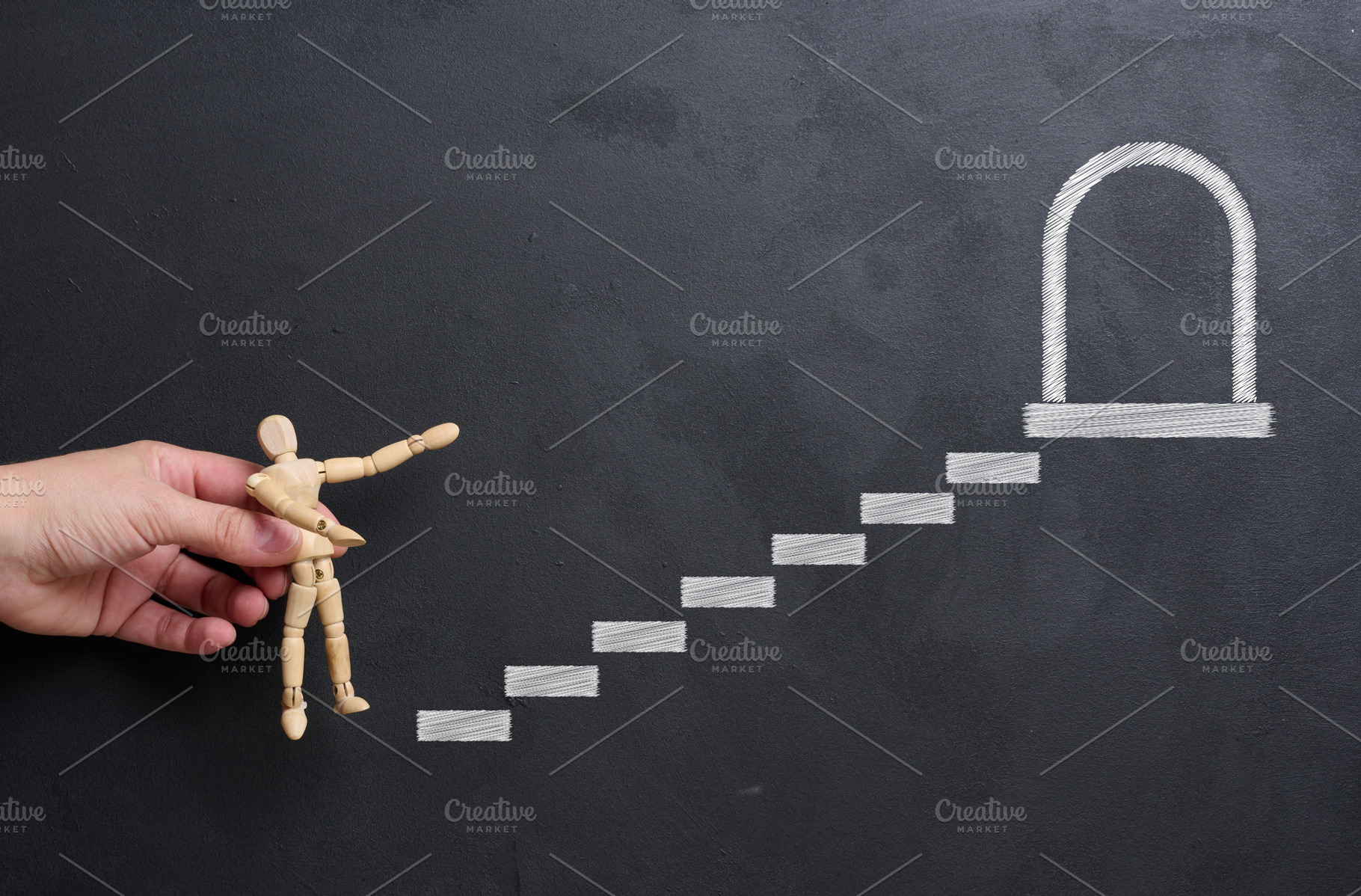 A woman's hand places a wooden mannequin on a chalk-drawn stairc, a Business Photo by ndanko