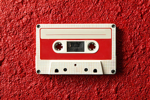 Old audio cassette placed on a red, a Photo by Pavel_design