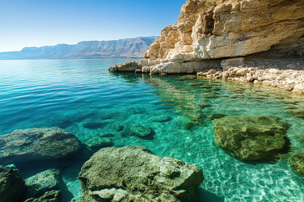 Crystal clear waters and serene rock, a Photo by Tanuart