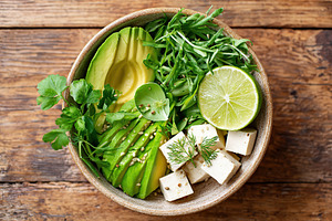 Vegan meal featuring fresh greens, avocado, tofu, and lime served in a rustic b, a Food & Drink Photo by AlyaAnd
