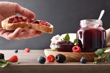 Hand showing slice of bread with berries jam for breakfast, a Food & Drink Photo by Davizro's Market