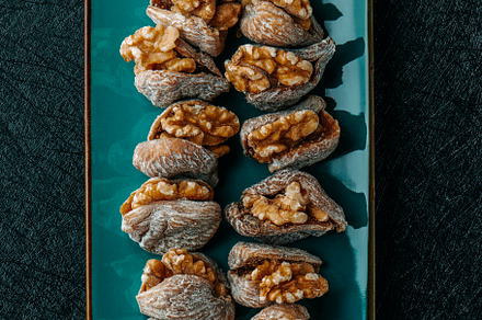 plate with some dried figs filled with walnuts, a Photo by Nito