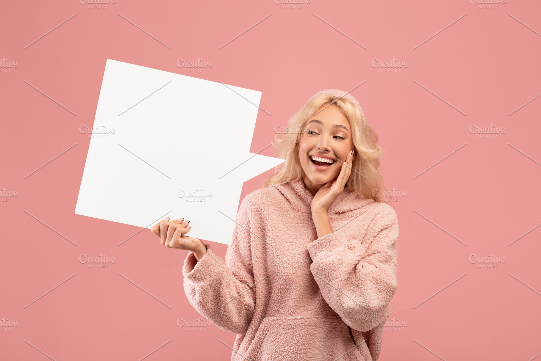 Overjoyed young woman holding and looking at blank speech bubble, posing on pin, a Photo by Prostock-Studio