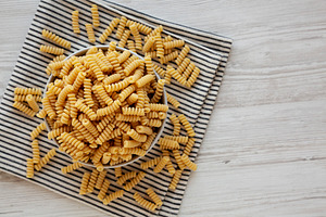Uncooked Organic Dry Fusilli Pasta in a Bowl, top view. Copy spa, a Food & Drink Photo by LiudmylaChuhunova