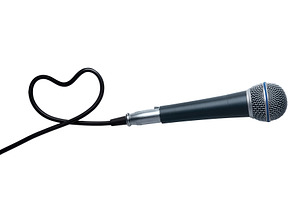 Black microphone with cord forming a heart shape on a white back, a Holiday Photo by Ales Munt