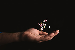 pills in hand on black background