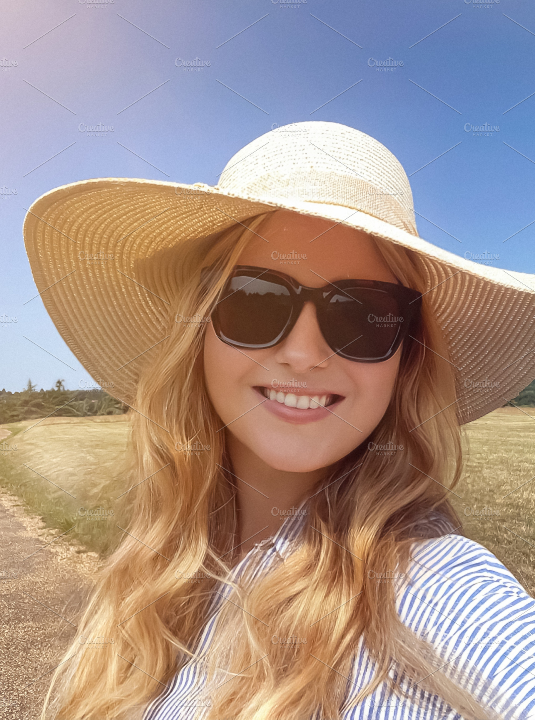 Country path stroll on a bright summer day, woman in straw hat a, a Person Photo by Studio ANNA