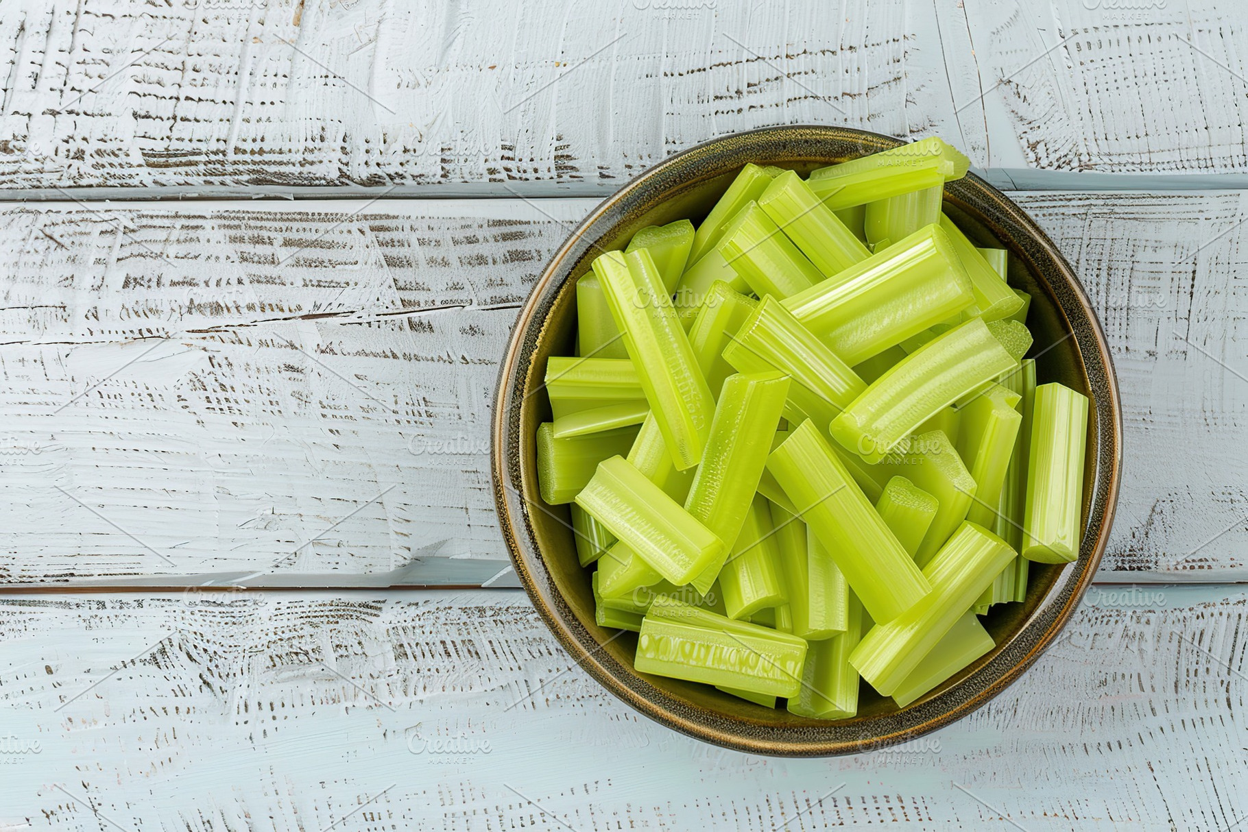 Green fresh celery pieces in bowl on wooden table, a Food & Drink Photo by AlyaAnd