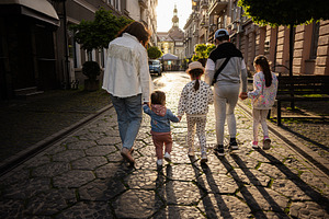 Family walking together on a sunlit cobblestone street during a spring evening, a Person Photo by AS photostudio