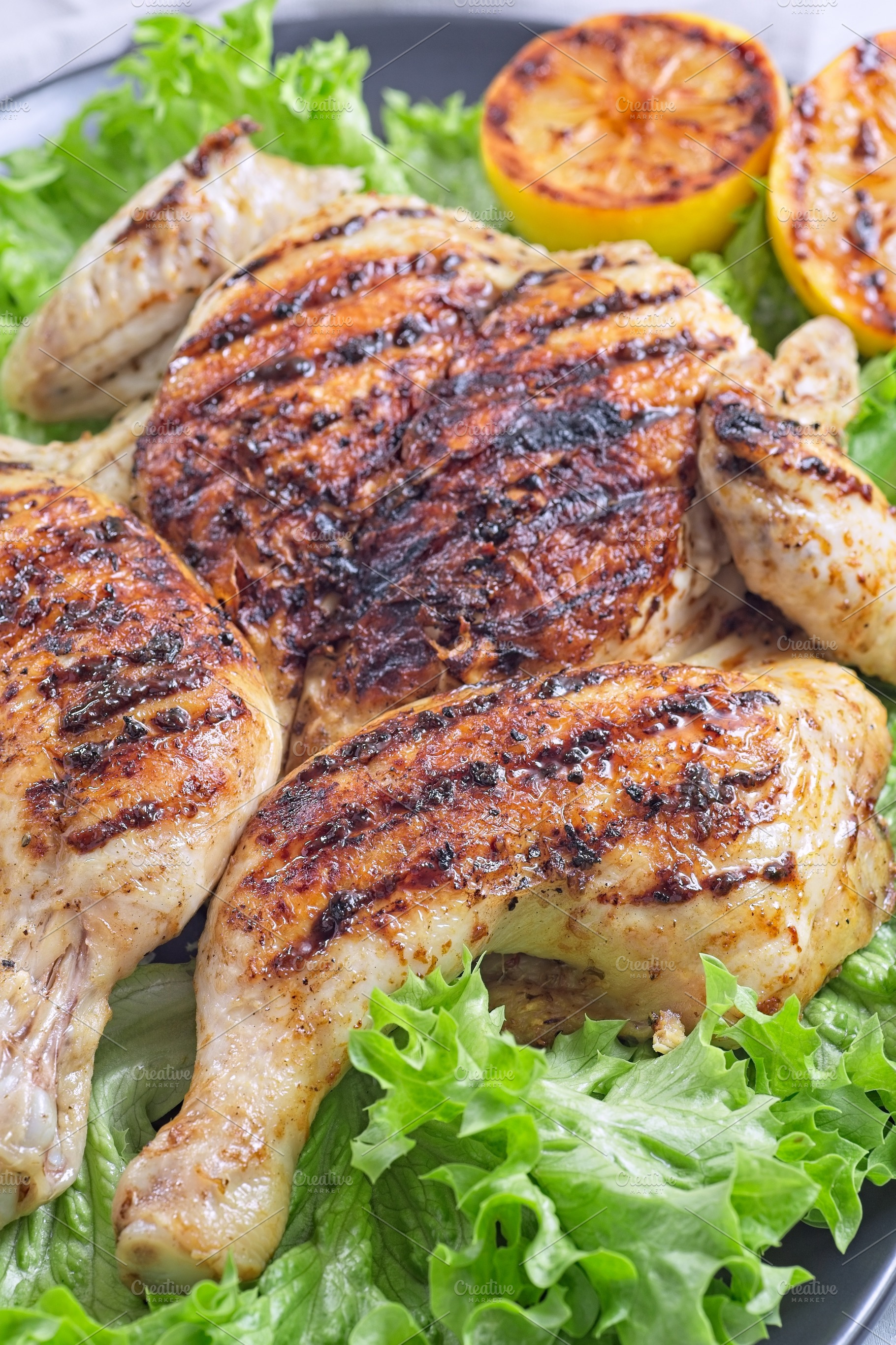 Grilled spatchcocked chicken with lemon garlic marinade, with lettuce and lemon, a Food & Drink Photo by iuliia_n