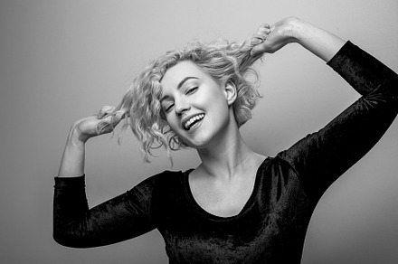Headshot of gorgeous attractive young lady with curly hair smiling. Black and w