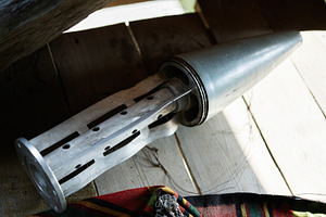 Close-up of vintage metal rocket shell component resting on wooden floor near c, a Photo by AS photostudio