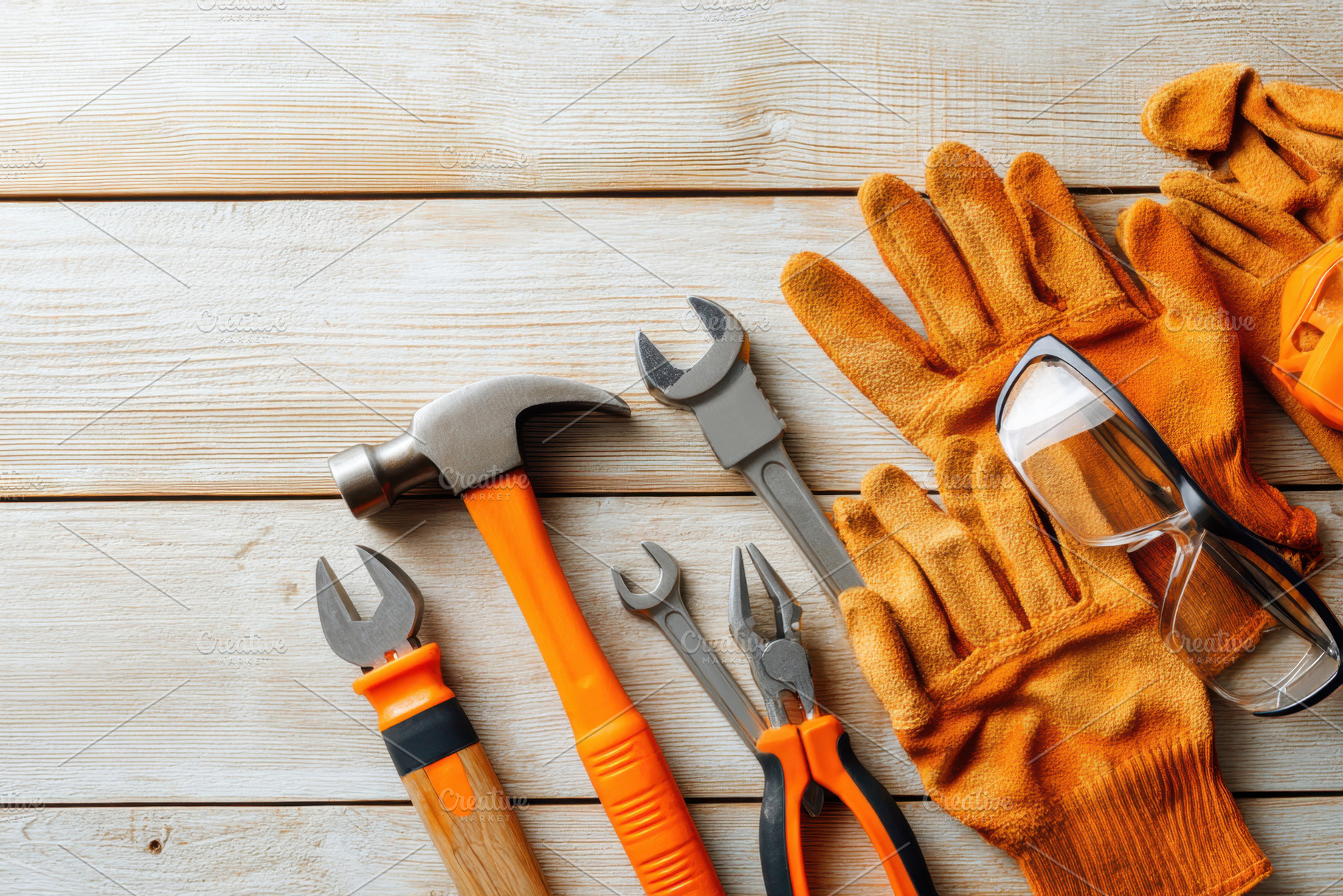 Hand tools and safety gear on wooden surface, an Industrial Photo by AlyaAnd