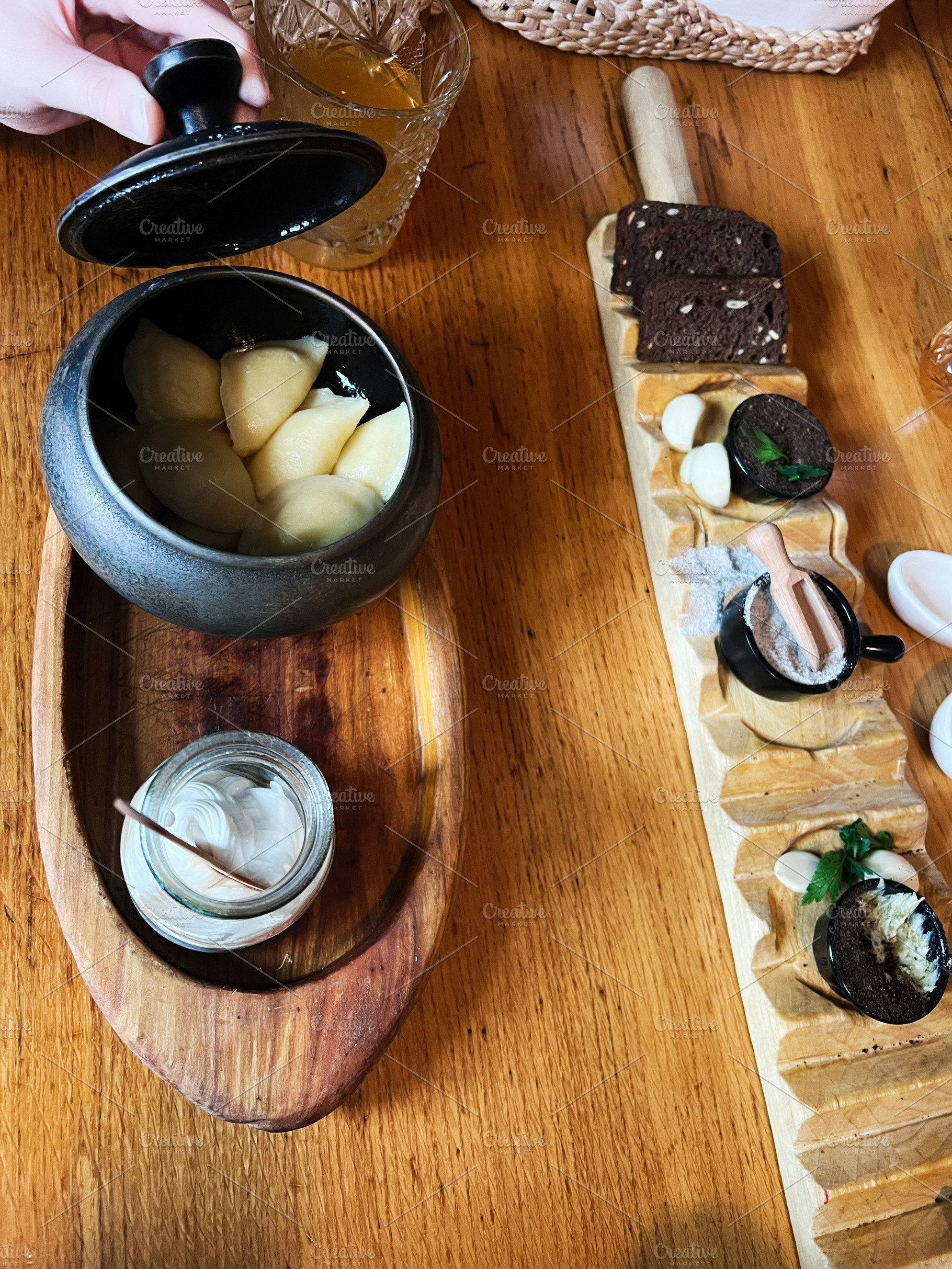 Appetizing meal presentation with dumplings, bread, and condiments on wooden pl, a Photo by AS photostudio