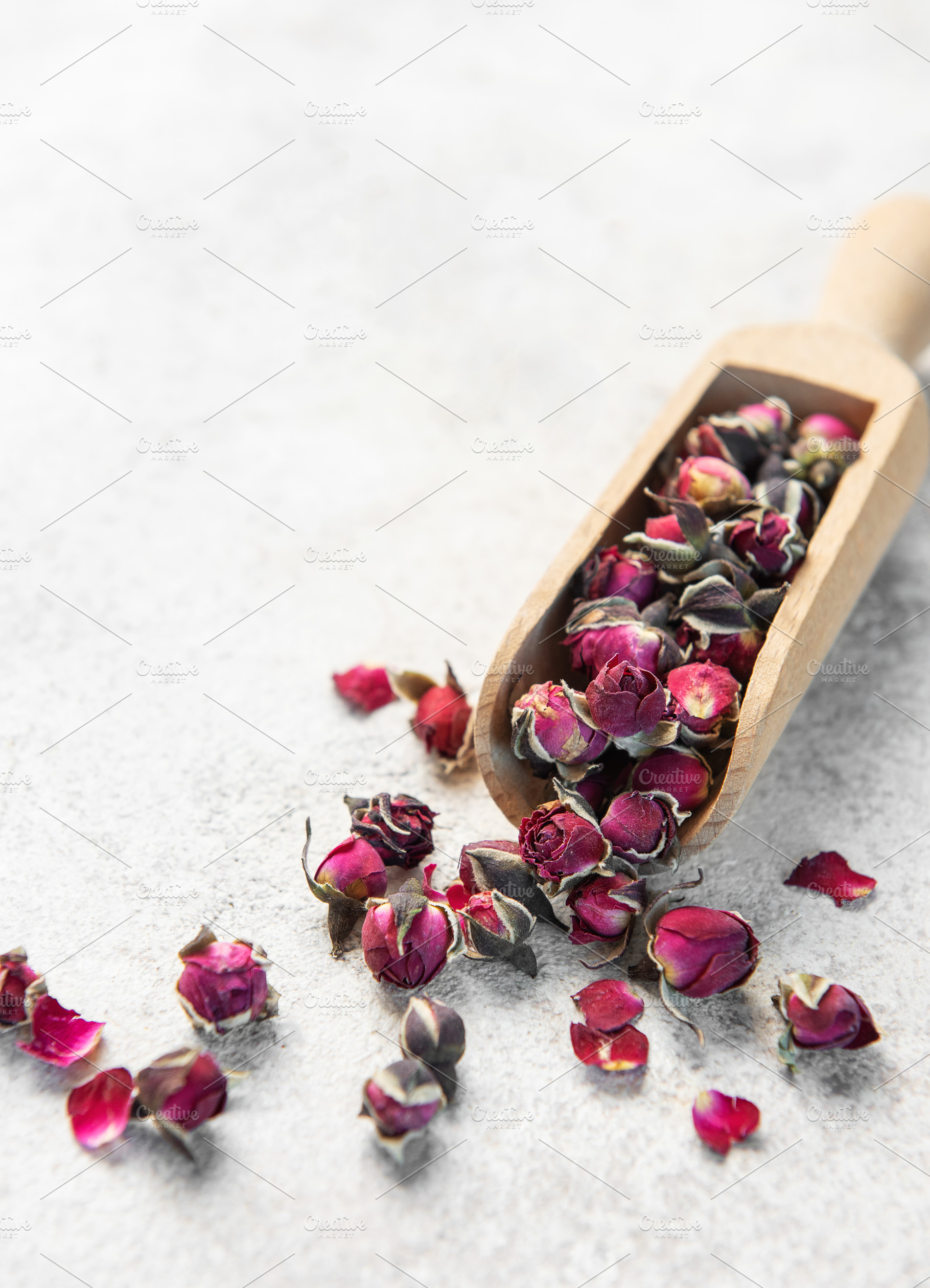 Dried rose buds spilling from wooden scoop, a Food & Drink Photo by Olena Rudo