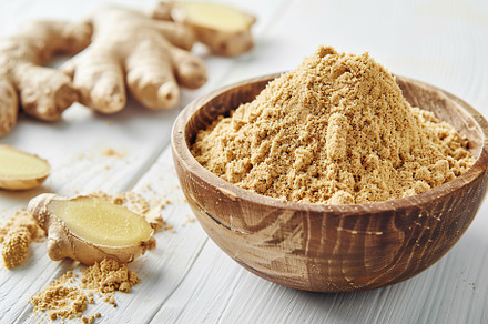 Ground dry ginger in bowl on wooden table, a Food & Drink Photo by AlyaAnd