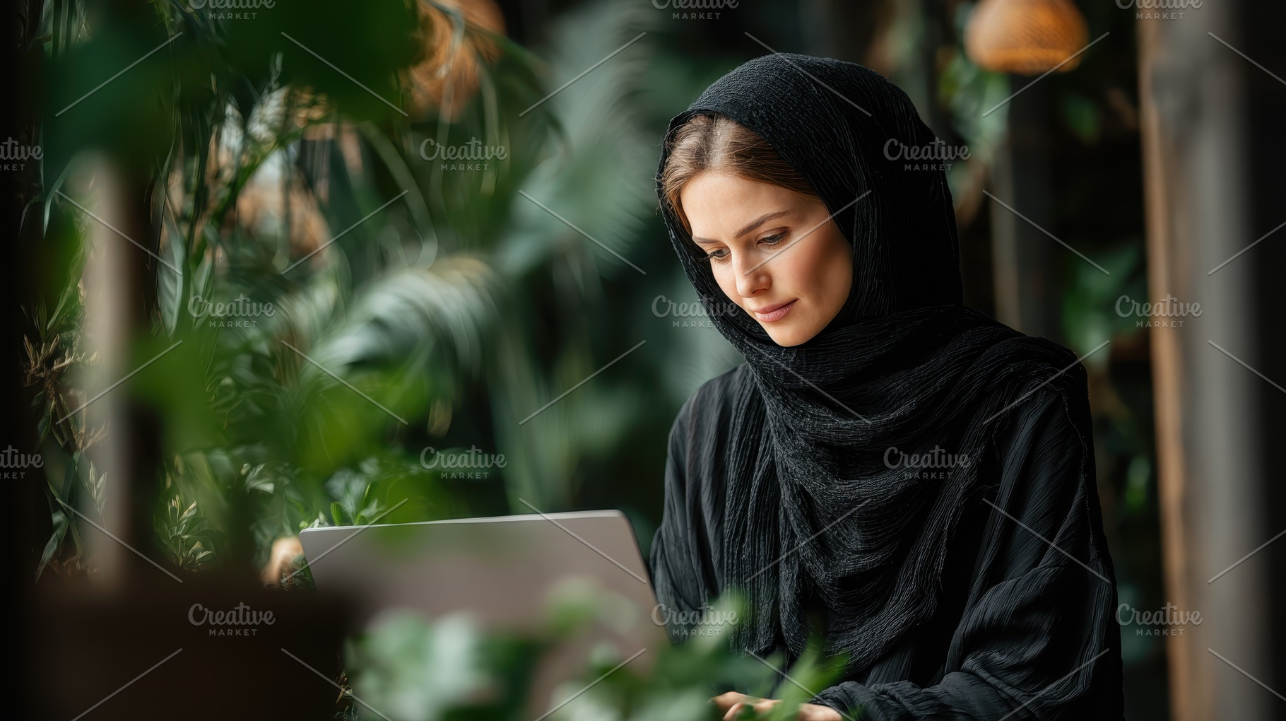 Woman in hijab using laptop amidst g, a Photo by Pixeness Studio