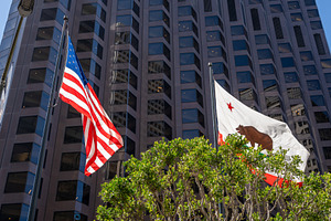 American and California flags waving in front of a modern buildi, an Architecture Photo by GoodGoods