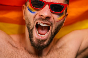 Excited man with face paint celebrating gay pride, a Photo by karrastock