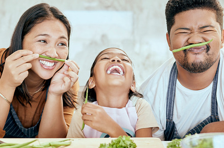 Happy asian family, play vegetables kitchen in portrait and smile together at table for bonding time. Mom dad, child happiness in comic home and health food in nutrition diet, dinner and kid cooking, a Photo by Peopleimages.com