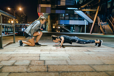 Woman doing push ups by supervision of personal trainer on the c