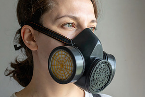 Woman wearing black gas mask looking away from window, a Person Photo by GoodGoods