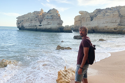 Man walking barefoot on a sandy beach in Algarve, Portugal,, a Photo by sebastianaraw