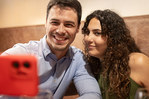 Happy couple taking selfie with smartphone while dining at restaurant, a Person Photo by etorres69