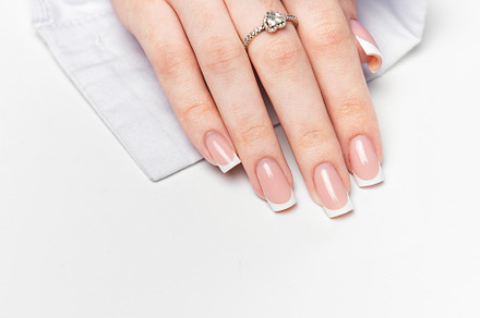 Woman hand showing french manicure and elegant ring on white bac