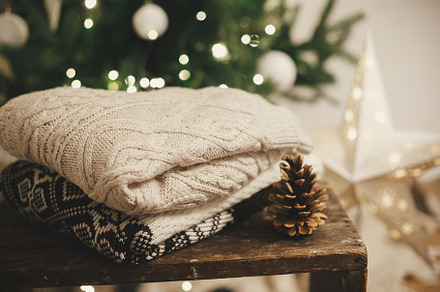 Cozy knitted sweaters on rustic wood with pine cone on backgroun, a Holiday Photo by Sonjachni