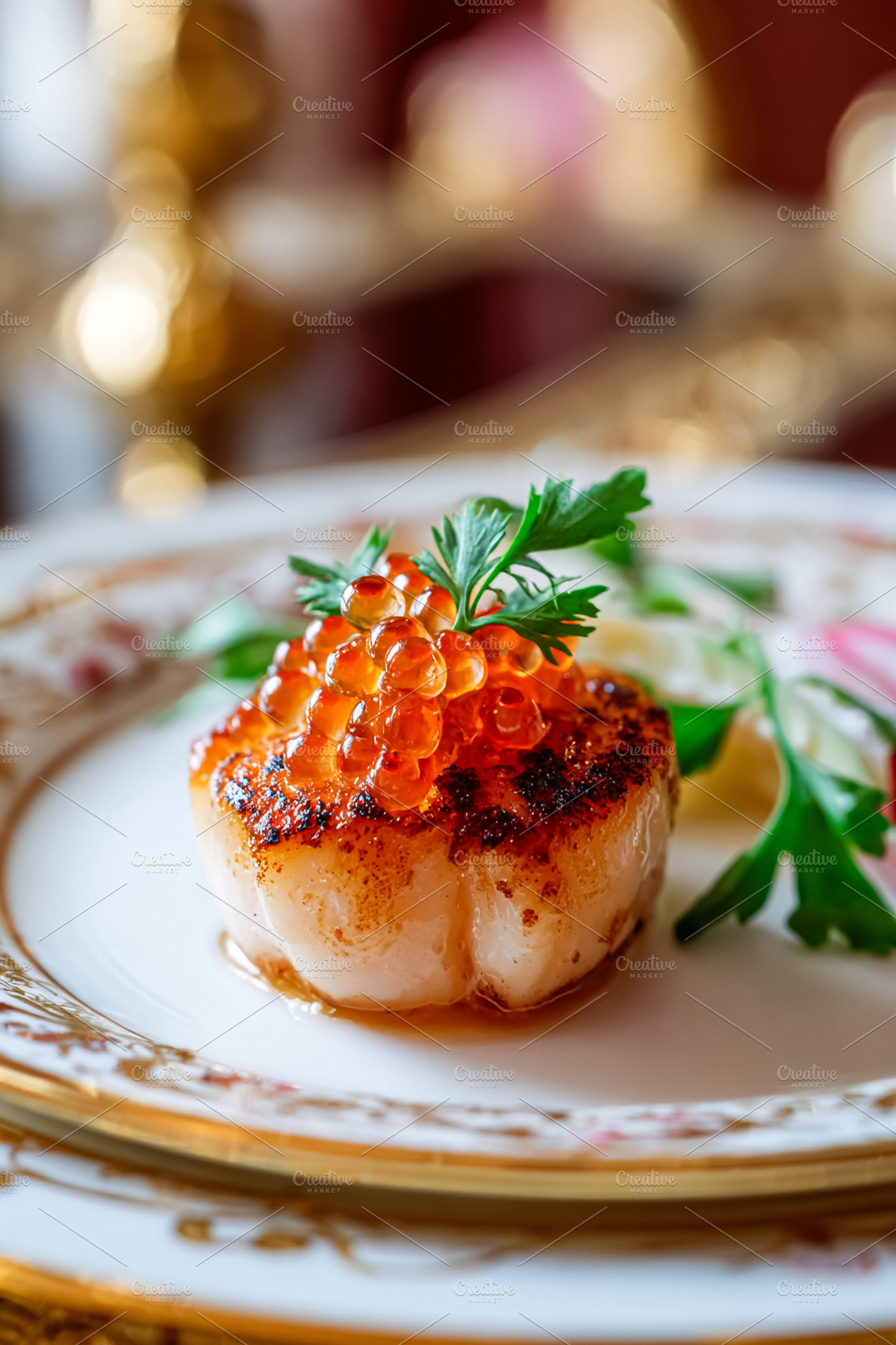 Seared scallop topping with red caviar and parsley, serving fine, a Food & Drink Photo by Studio ANNA