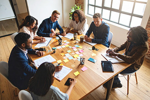 Young professionals engaged in a brainstorming session around a, a Business Photo by DanFLCreativo