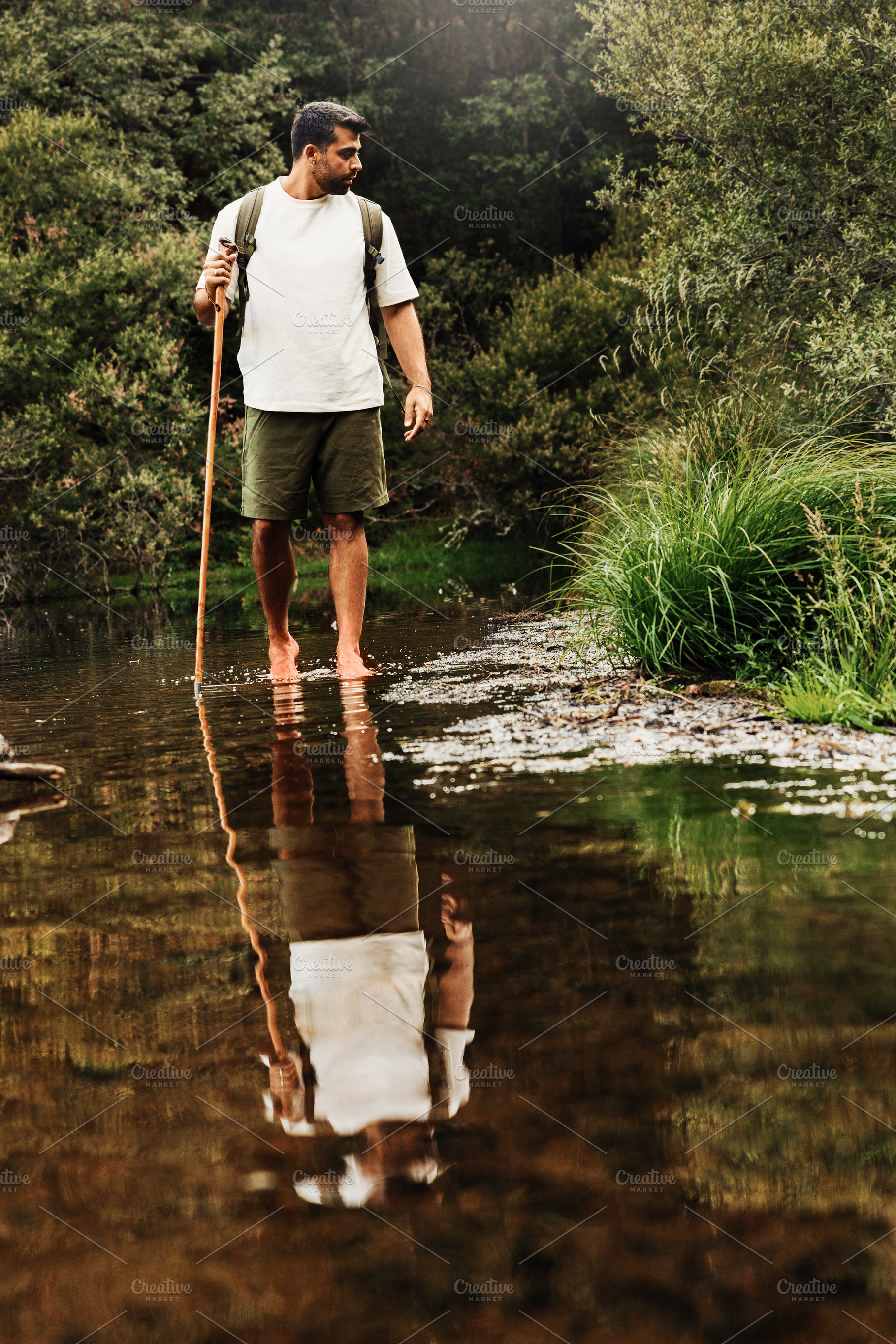 Hiker crossing a stream barefoot in, a Person Photo by Perpis