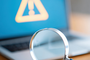 Magnifying glass and envelope with warning on laptop, a Business Photo by AlyaAnd