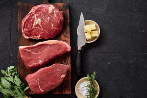 Fresh raw rib-eye, roast beef, flank, and rump steak displayed on a wooden cutt, a Food & Drink Photo by Asya Nurullina