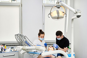 Male dentist in surgical glove and mask doing dental treatment of patient with, a Health & Medical Photo by Rohan Photography