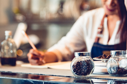 Closeup of coffee bean bottle and happy Female barista write dow, a Business Photo by Ministocker