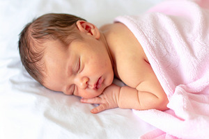 Photo of a newborn baby sleeping peacefully on a white bed, wrap, a Person Photo by DanFLCreativo