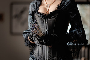 Beautiful woman in vintage black dress holding a dry lavender fl