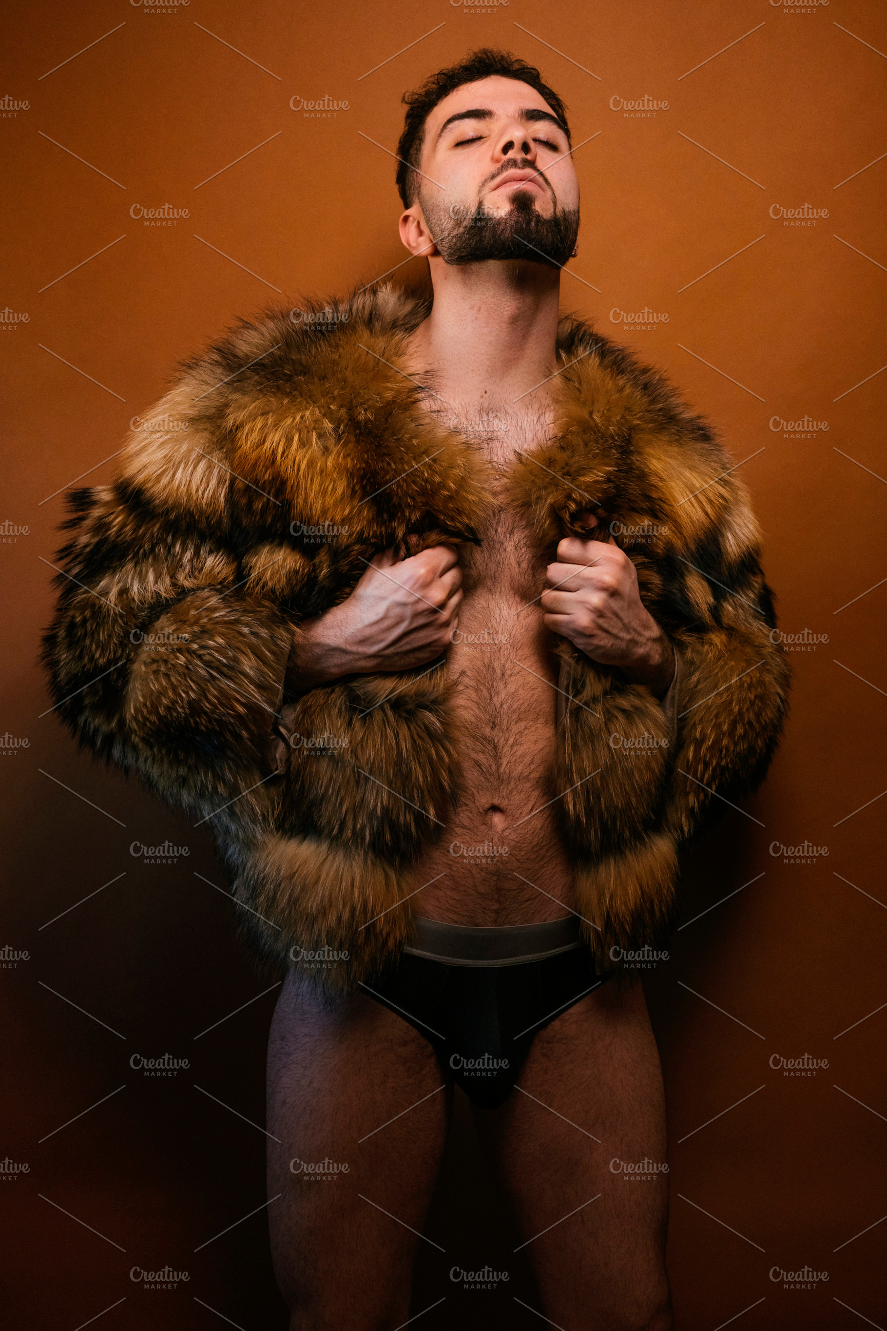 Young man posing in fur coat for pride concept, a Photo by karrastock