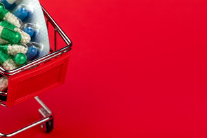 Mini shopping cart filled with various medication capsules and blister packs on, a Health & Medical Photo by Ales Munt