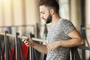 Young man using smartphone while waiting at the train station, an Abstract Photo by Antonio Gravante Market