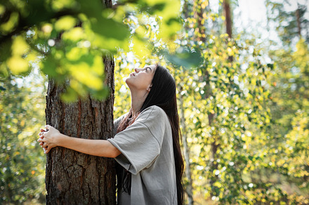 Young woman enjoying a peaceful moment by a tree in a lush green, a Person Photo by Olena Rudo